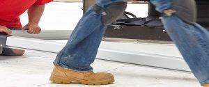 close up of a person wearing jeans and boots walking on a commercial flat roof