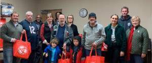 a small group of employees with their families holding red bags for a charitable giving campaign