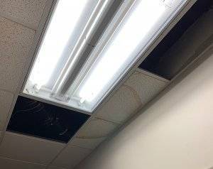 an office light troffer with ceiling tile beginning to stain due to a water leak