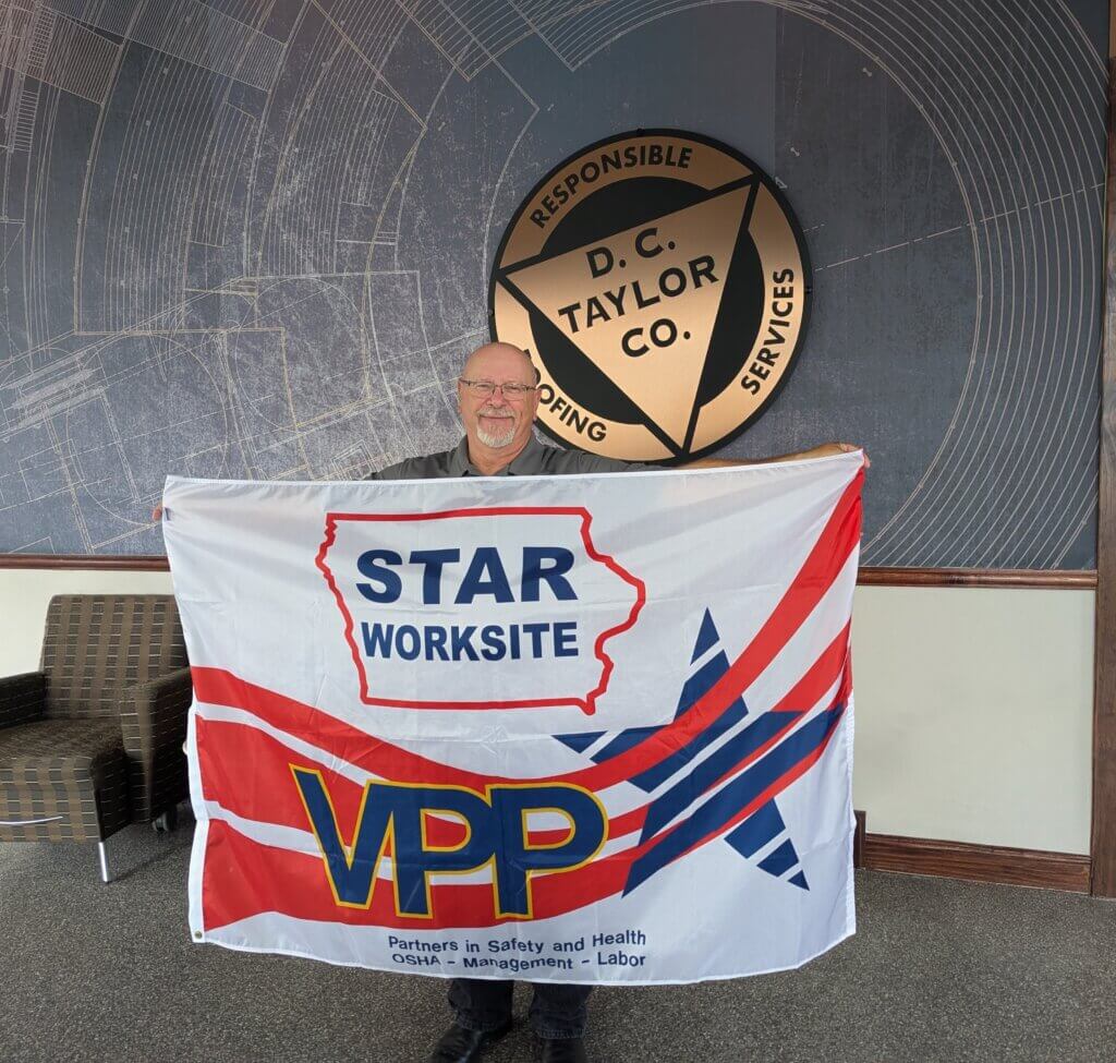 Safety manager Kirk Dighton holds up the Iowa OSHA Star Worksite flag